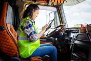 A female truck driver plans her schedule for the day inside her truck.